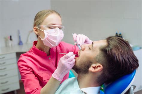 Professional Teeth Cleaning Dentist Cleans The Teeth Of A Male Patient