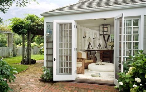 A Small White Shed With An Open Door And Patio Furniture In The Back