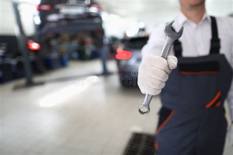 Car Repairman In Uniform Holds Wrench In Car Workshop Stock Photo