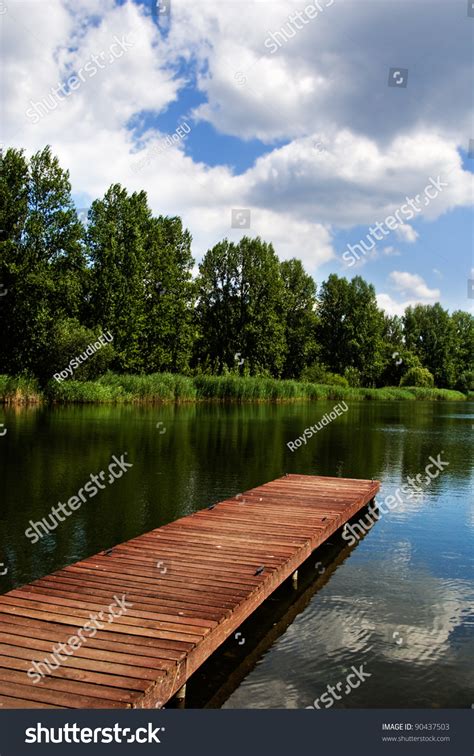 A Wooden Dock Pier On A Lake In Summer Sunny Day Blue Sky White