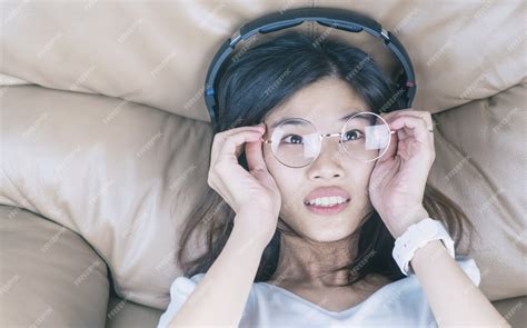 premium photo nerdy asian girl with glasses is listening to music on her headphone