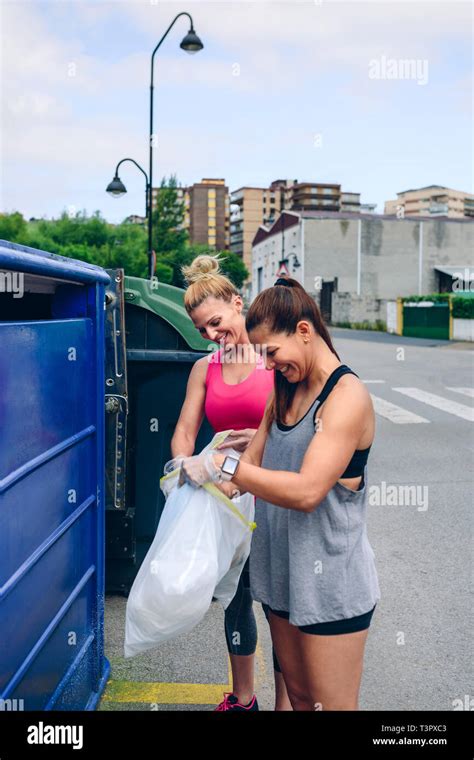 Las niñas a tirar la basura en el contenedor de reciclaje Fotografía de