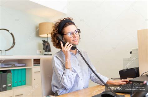 Receptionist Talking On Telephone At Desk In Hotel — Occupation On The