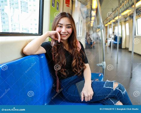 Glad Ethnic Asian Female Passenger Sitting In Train Wagon And Leaning On Hand While Looking At