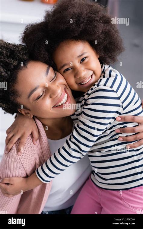 Joyful African American Mom And Daughter Embracing At Home Stock Photo