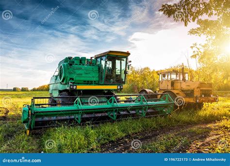 The Modern Green Combine Harvester And Yellow Heavy Duty Tractor On