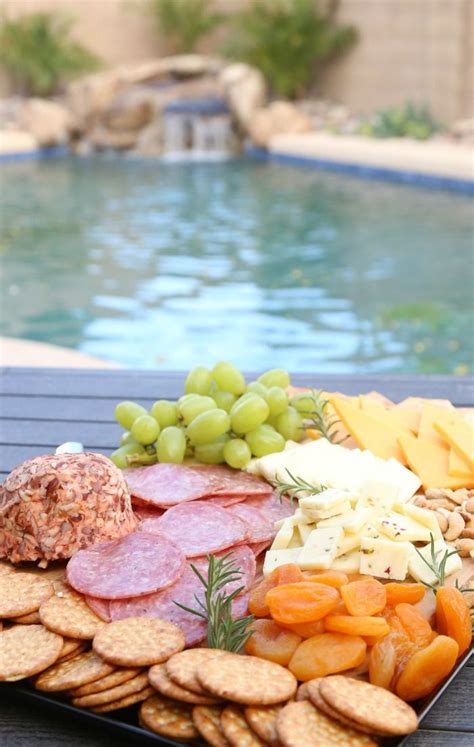 An Assortment Of Cheeses Meats And Crackers On A Platter By A Pool
