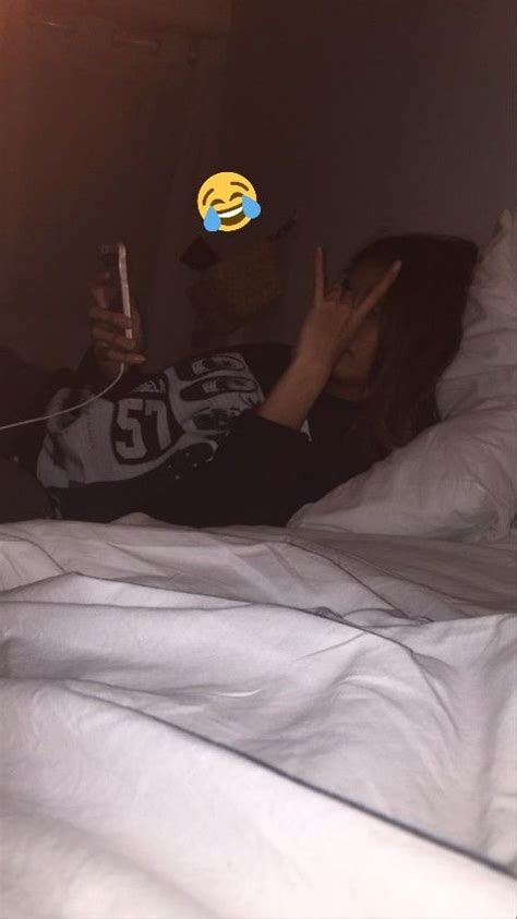 A Woman Laying In Bed With Her Hand Up To Her Face While Holding A Cell Phone