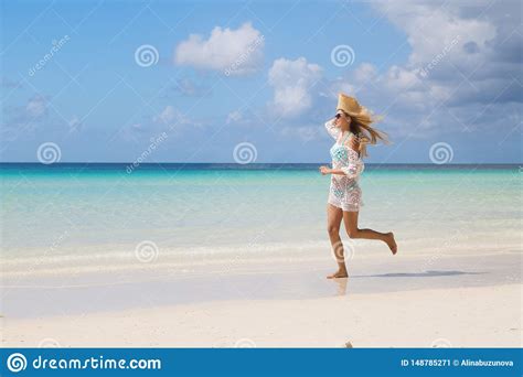 Tanned Girl In Blue Bikini And White Tunica Running On The Seashore