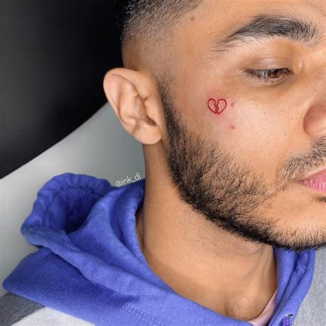 Broken Heart Tattoo Done On The Face Using Red Ink