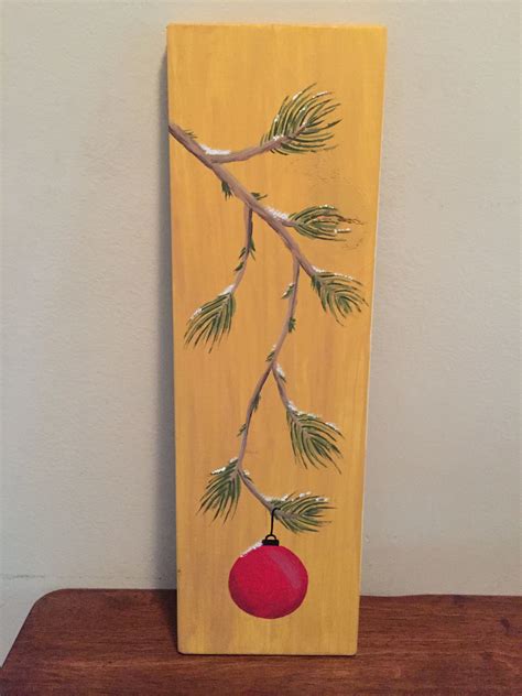 Hand Painted Ornament Hanging From Pine Tree Branch On Wood Plank