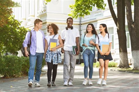 Happy University Students Walking Together On Campus Chatting And