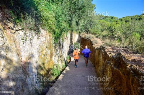 Barcelona Spain Two Men Walk Along A Narrow Path In Guell Park By