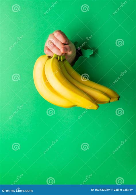 A Woman Holds A Banana In Her Hand Inserted Through A Hole In Torn