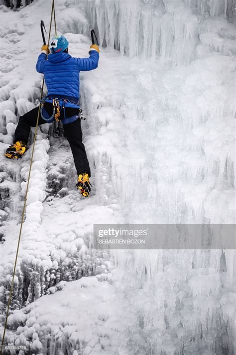 A Person Climbs An Artificial Frozen Waterfall At A Ski Resort In