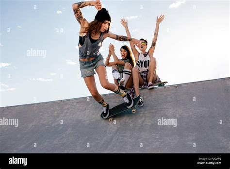 Skater Girl Rides On Skateboard With Female Friends Sitting On Ramp