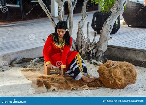 Young Maldivian Girl In Red National Clothes Working On Crude Editorial