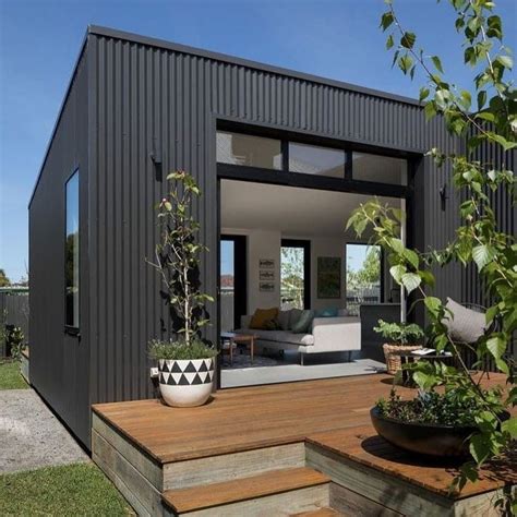 A Black House With Wooden Steps Leading Up To The Front Door And Outside Patio Area