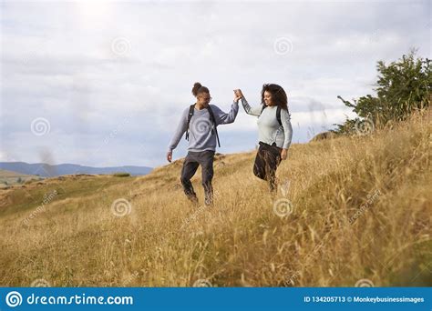 Young Adult Mixed Race Couple Walking Down A Hill Hand In Hand During A