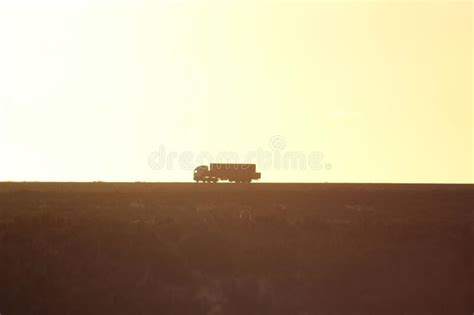 A Single Truck Traveling On A Dirt Road With Sunset In The Background