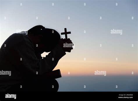 silhouette of woman kneeling down praying for worship god at sky background christians pray to