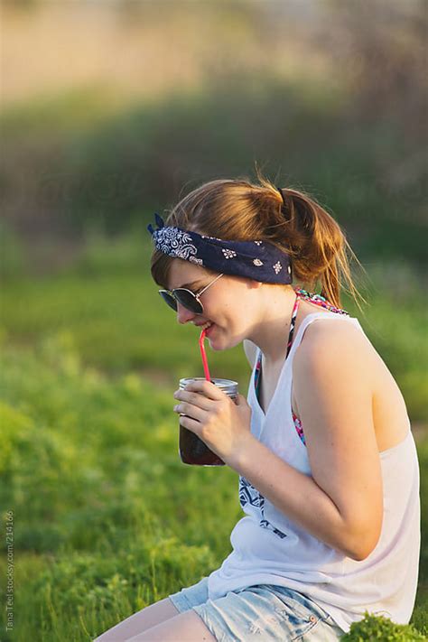 Teen Girl Sipping Her Drink From A Straw In A Jar On A Summer Day By