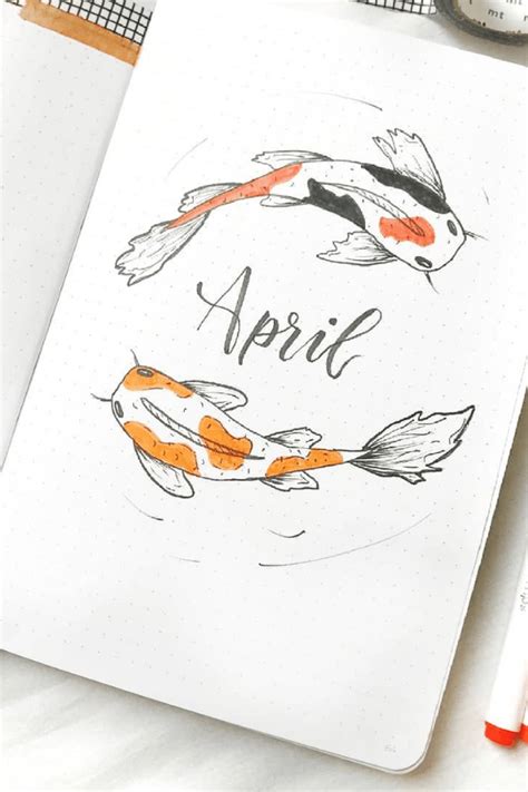 An Open Notebook With Two Orange And Black Koi Fish On It Next To Some
