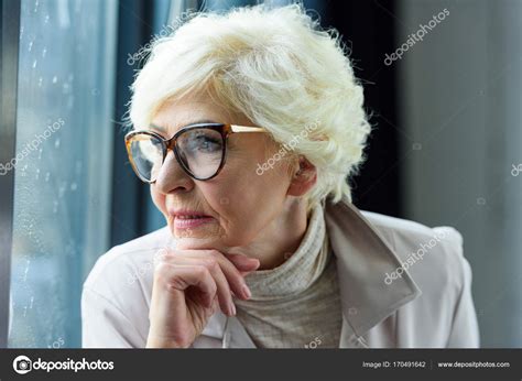 Пожилая женщина смотрит в окно Стоковое фото AllaSerebrina