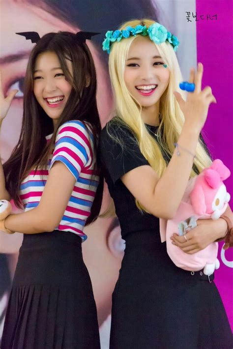 Two Young Women Standing Next To Each Other In Front Of A Purple Wall