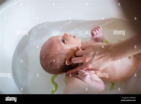 Unrecognizable Mother Bathing Her Son In White Small Plastic Bat Stock
