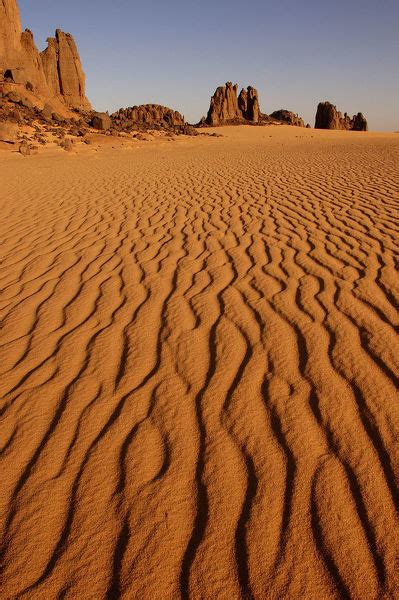 Patterns In Desert Sand With Rock Formations In Background