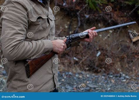 A Man Holds An Old Antique Double Barrel Shotgun To His Waist