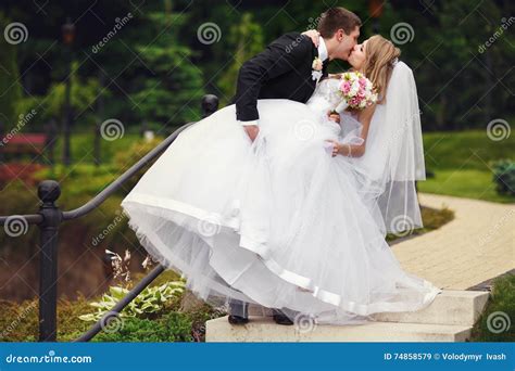 Groom Holds Bride S Leg While Kissing Her In A Park Stock Image Image