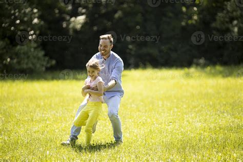 Father Chasing His Little Daughter While Playing In The Park 16602667