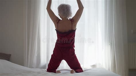 Wide Shot Back View Slim Mature Woman Stretching Sitting On Bed In The Morning Happy Rested