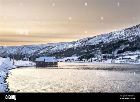 Red Wooden House In The Wintry Snow Covered Landscape By The Fjord In