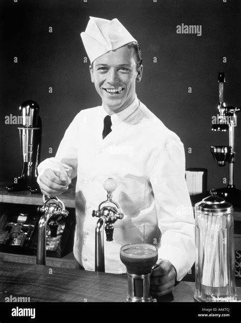 1940s 1950s Smiling Young Man Soda Jerk At Counter Serving An Ice Cream