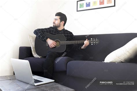 Man Playing Guitar Sitting On Sofa — Wireless Technology Flat Stock