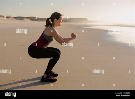 Shoot Of A Beautiful Woman Making Squats Exercises In The Beach Stock