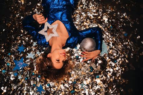 A Woman In A Blue Sequined Dress Smiles And Lies On The Floor Under A Falling Multicolored