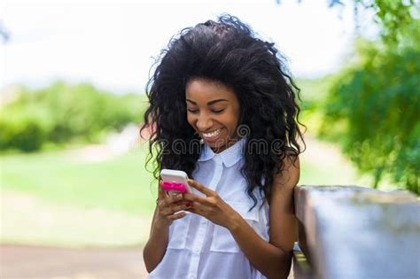 Outdoor Portrait Of A Teenage Black Girl Using A Mobile