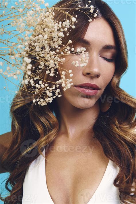 Portrait Of Beautiful Young Woman Keeping Eyes Closed While Standing Against Blue Background