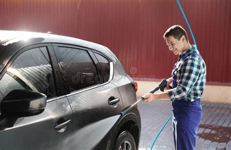 Worker Cleaning Automobile With High Pressure Water Jet Stock Photo