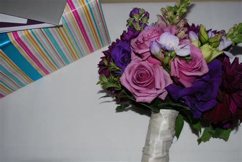 A Bouquet Of Purple And Pink Flowers Sitting On Top Of A Table Next To