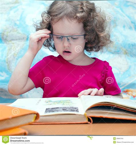 Petite Fille Intelligente Avec Des Glaces Affichant Un Livre Photo
