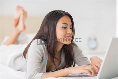 Pretty Girl Lying On Bed Using Her Laptop By Wavebreakmedia Vectors And Illustrations With