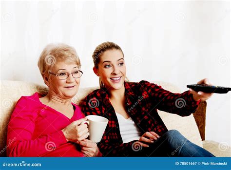 Portrait Of Granddaughter And Grandmother Sitting On Couch And Watching Tv Stock Image Image