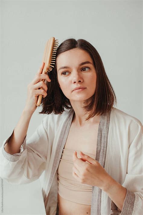 Minimalistic Portrait Of Woman At Home Combing Her Hair And Looking