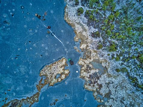 Aerial View Of Two Fishermen Walking On Surface Of Frozen Lake Stock Photo