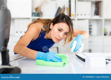 Mexican Woman Wearing Uniform Cleaning Table In Office Stock Image